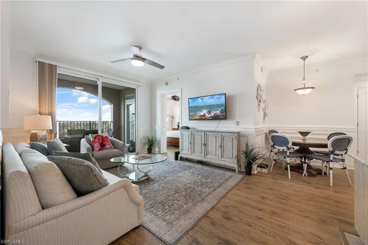 Living room with wood-type flooring, ornamental molding, and ceiling fan