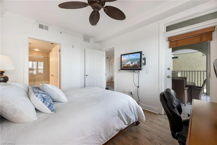 Bedroom with crown molding, ensuite bath, ceiling fan, access to exterior, and hardwood / wood-style floors