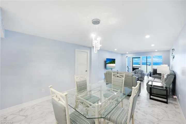 Dining space with marble finish floors, a chandelier, and recessed lighting