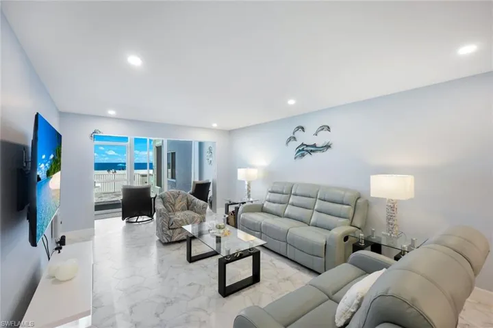 Living area with light marble finish floors and recessed lighting