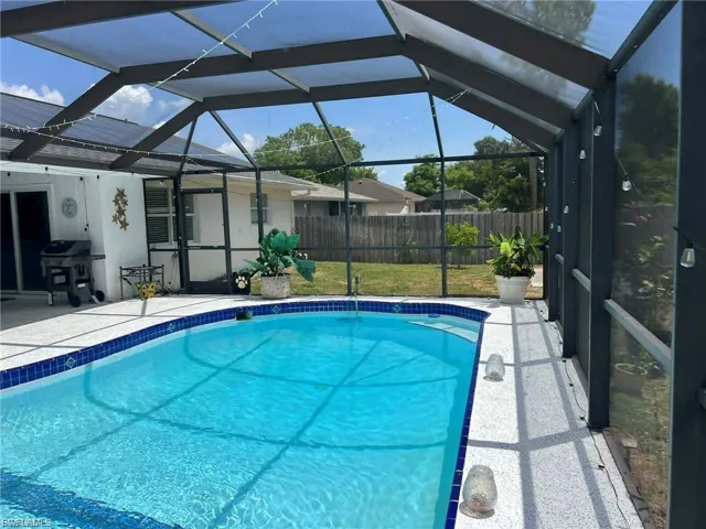 Screened-in pool enclosure featuring a rectangular pool with blue tile accents