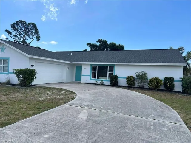 White exterior with vibrant blue trim, attached two-car garage, and a curved concrete driveway