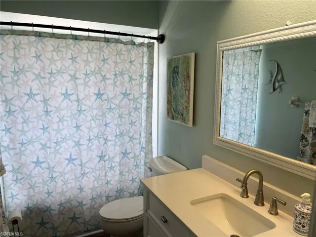 White vanity with integrated sink, brass-finish faucet, and framed mirror
