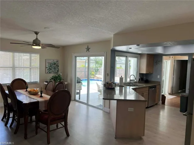Open-concept kitchen and dining area with wood-finish flooring, recessed lighting, and a ceiling fan