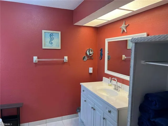 White vanity with a single basin sink, chrome faucet, and white countertop