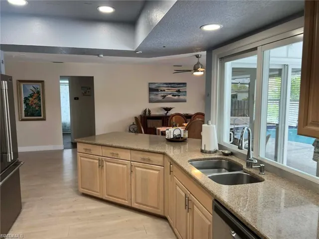 Kitchen island featuring an undermount double basin sink, stainless steel faucet, and light-toned cabinetry