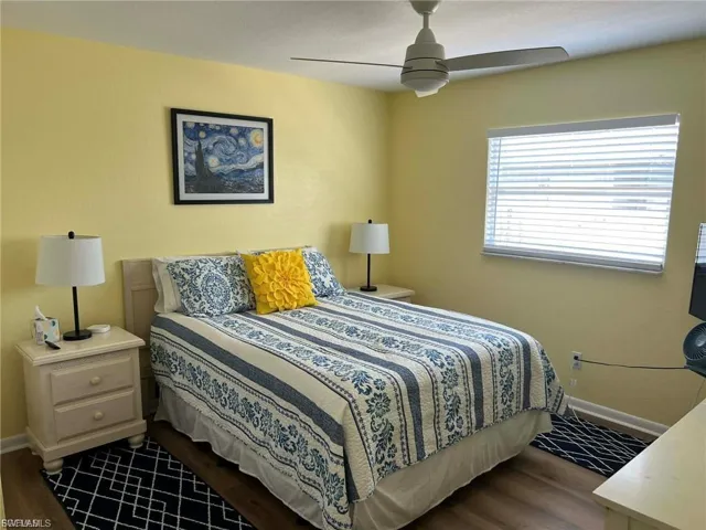 Ceiling fan with light fixture, window with horizontal blinds, wood-finish flooring, and painted walls