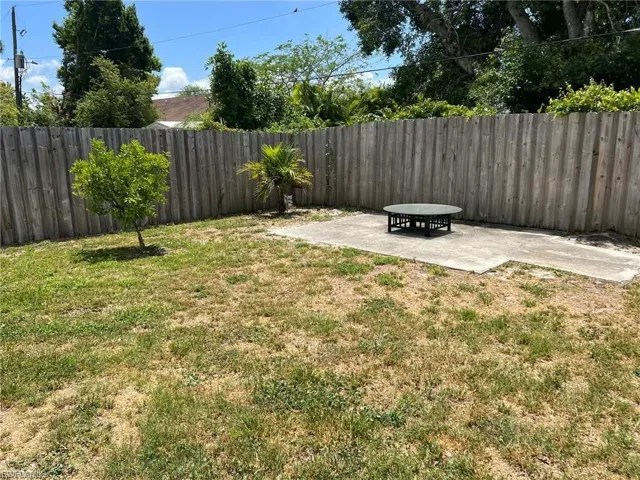 Private backyard featuring a wooden fence, concrete patio, and established trees