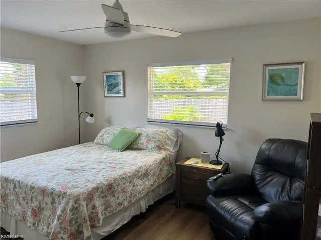 Room featuring wood-finish flooring, two windows with blinds, a ceiling fan, and light-toned wall paint