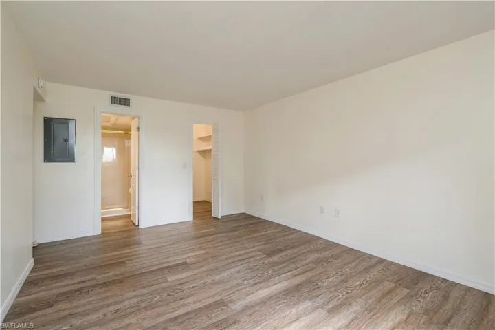 Spare room with electric panel and hardwood / wood-style floors