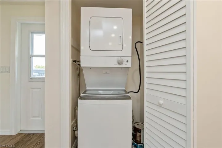 Washroom featuring hardwood / wood-style flooring and stacked washer / dryer