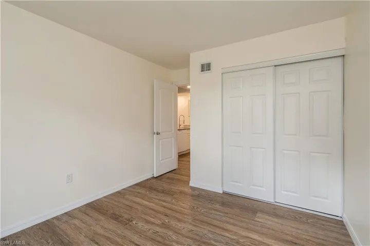 Unfurnished bedroom with wood-type flooring, sink, and a closet