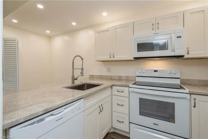 Kitchen featuring sink, white appliances, and white cabinets