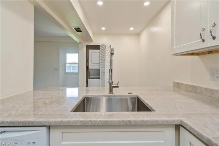 Kitchen with light stone counters and white cabinets