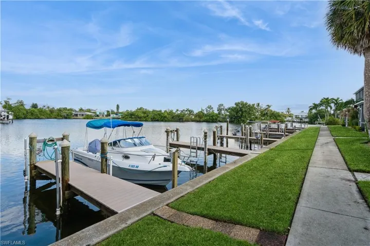 View of dock with a lawn and a water view