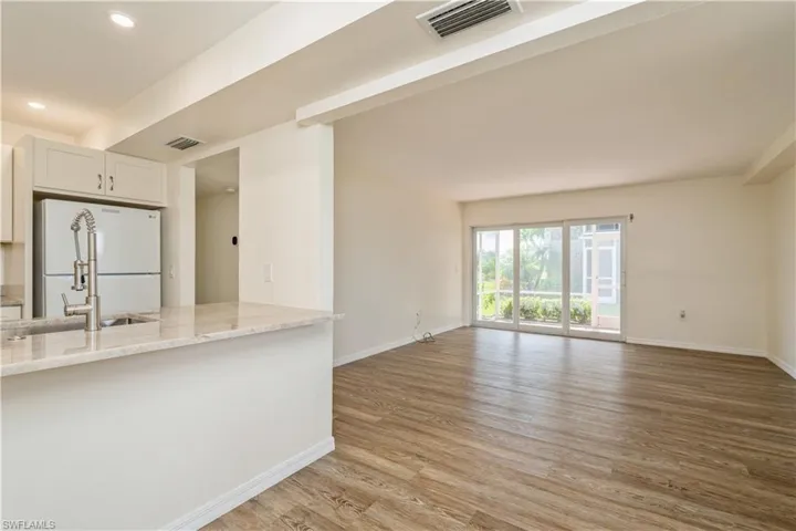 Kitchen featuring light hardwood / wood-style flooring, white refrigerator, white cabinets, and light stone countertops