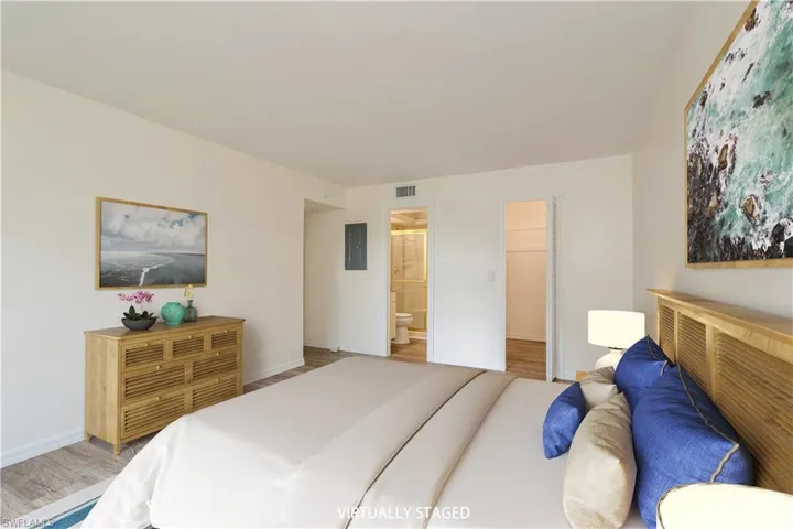 Bedroom featuring ensuite bath, hardwood / wood-style floors, electric panel, a closet, and a spacious closet