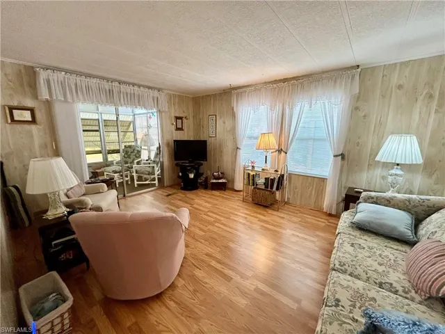Living room featuring wooden walls, hardwood / wood-style floors, and a textured ceiling