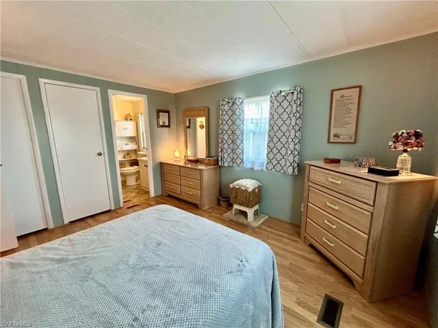 Bedroom featuring light hardwood / wood-style flooring, ensuite bath, and crown molding