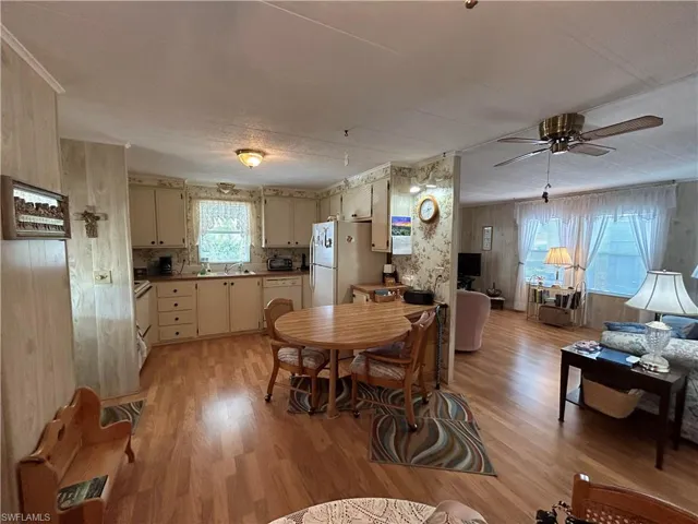 Dining area featuring a textured ceiling, ceiling fan, sink, light hardwood / wood-style floors, and wood walls