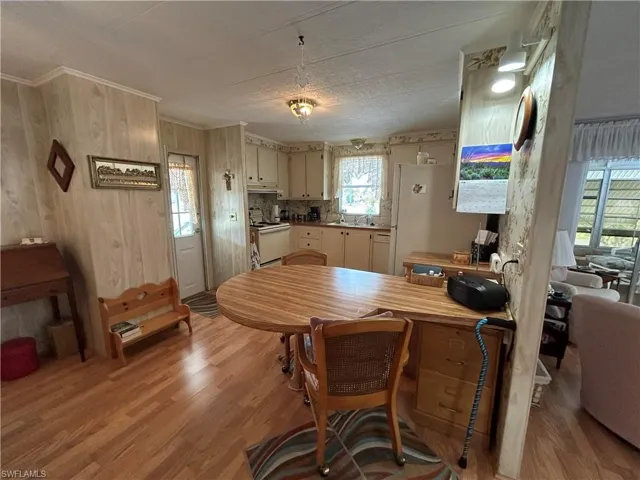 Kitchen featuring wood walls, white appliances, cream cabinets, sink, and light hardwood / wood-style flooring