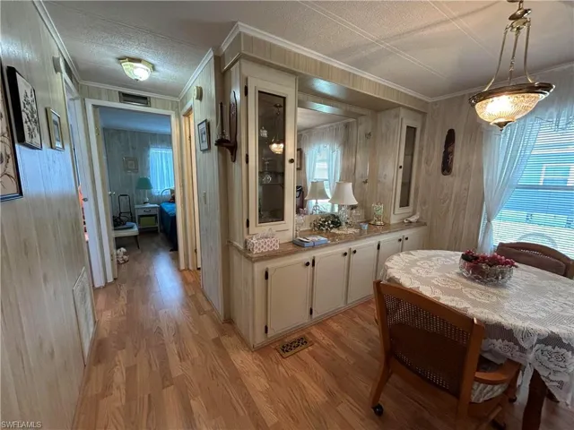 Kitchen featuring wood walls, decorative light fixtures, light hardwood / wood-style floors, and ornamental molding