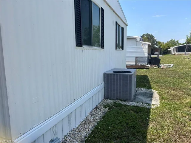 View of property exterior featuring a lawn and central AC