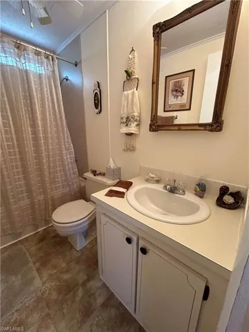 Full bathroom with vanity, a textured ceiling, shower / bath combo with shower curtain, crown molding, and toilet