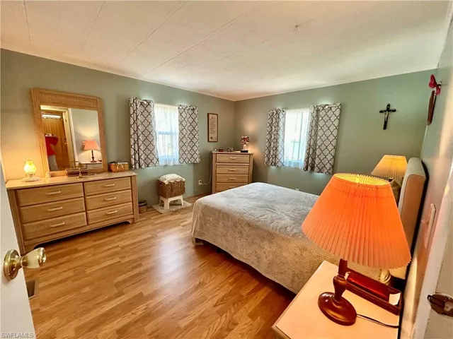 Bedroom with a textured ceiling, light hardwood / wood-style flooring, and multiple windows