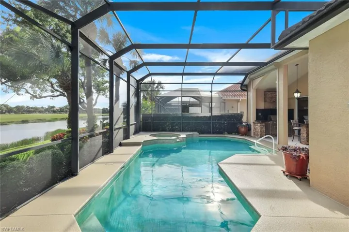 View of swimming pool with a lanai, a patio, a water view, area for grilling, and an in ground hot tub