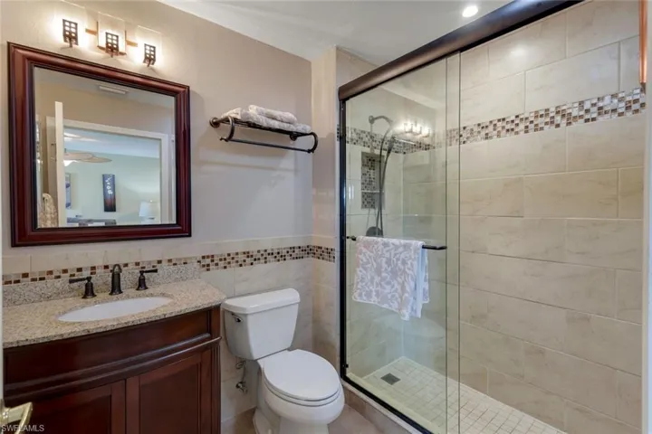 Updated BR2 Ensuite Bathroom with an enclosed shower, elevated vanity, toilet, and tile walls