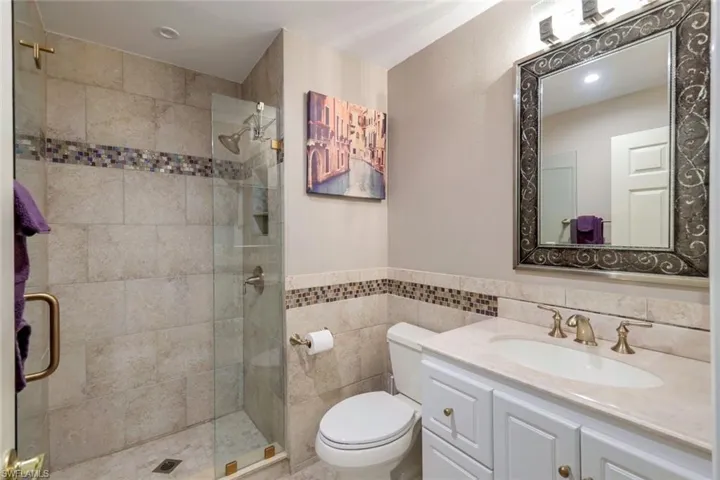 Updated BR#3 Ensuite Bathroom with vanity, toilet, an enclosed shower, and tile walls