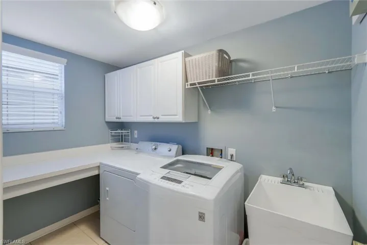Laundry room featuring folding and hanging areas, cabinets, separate washer and dryer, window and sink
