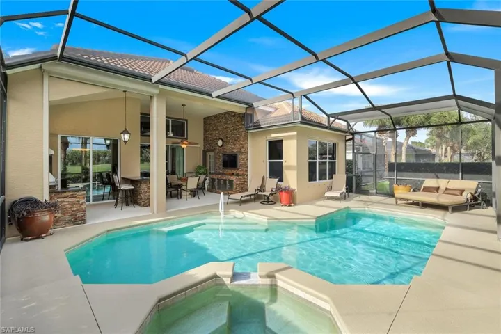 Furnished pool/lanai viewing outdoor living space, an in ground hot tub, and an outdoor bar.Exclude dining table and chairs. Gas heated pool.