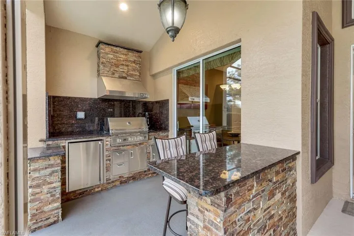 Summer kitchen on screened lanai with grilling area, exterior bar