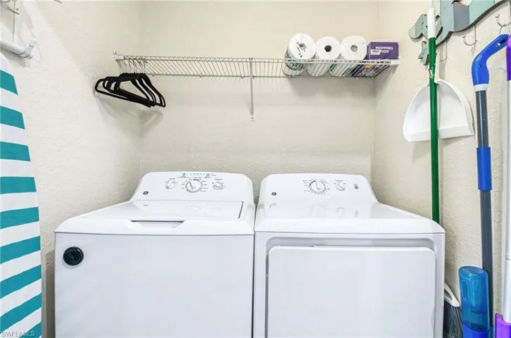 Laundry area featuring a top-load washing machine, front-load dryer, and an overhead wire shelving unit