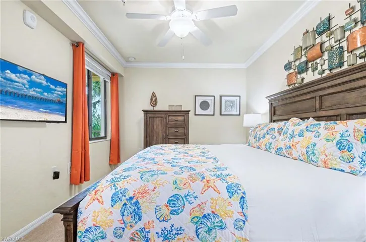 Bedroom featuring a dark wood bed frame with a paneled headboard, crown molding, and a ceiling fan