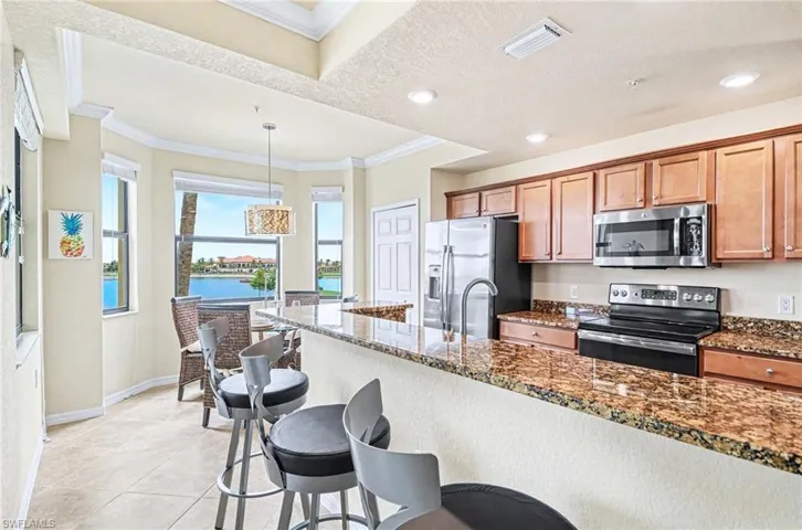 Kitchen featuring wood cabinetry, stainless steel appliances, and a granite countertop breakfast bar with seating