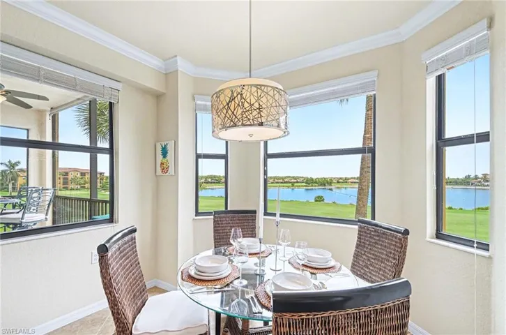 Dining area featuring multiple windows, a decorative overhead light fixture, light-toned walls, crown molding, and tiled flooring