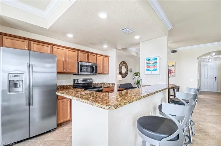 Modern kitchen featuring granite countertops, wood cabinetry, stainless steel appliances, and recessed lighting
