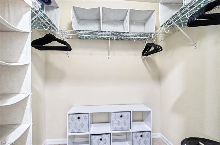Walk-in closet featuring wire shelving, multiple hanging rods, and a built-in storage unit