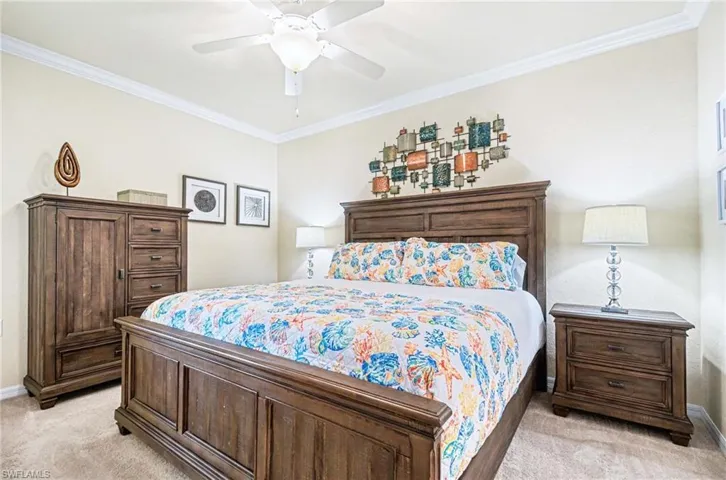 Carpeted bedroom featuring crown molding, a ceiling fan, and light-toned wall paint