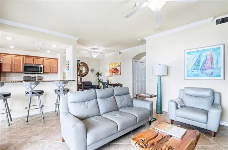 Open-concept living space featuring tile flooring, crown molding, and recessed lighting