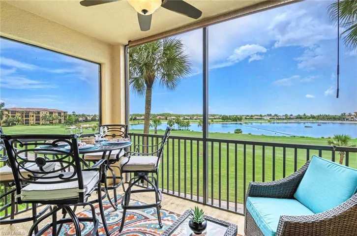 Screened balcony featuring a ceiling fan, a partial golf course, and a body of water extending to the horizon