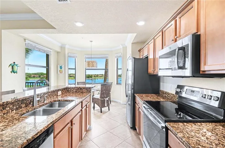 Kitchen featuring granite countertops, wood cabinetry, stainless steel appliances, and a dual basin sink