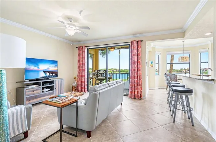 Open-concept living space featuring tile flooring throughout, crown molding, and a ceiling fan