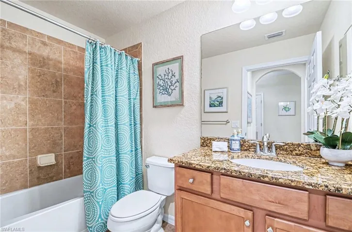 Bathroom featuring a built-in vanity with a granite countertop and an undermount sink
