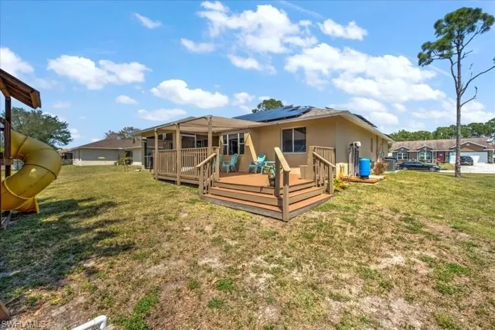 Back of house with a lawn and a wooden deck