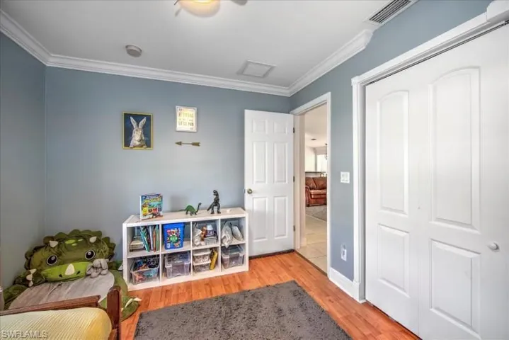 Rec room with ornamental molding and light tile floors