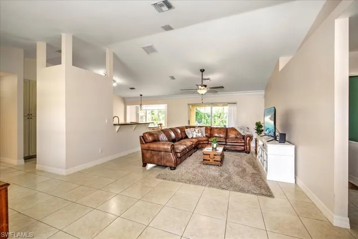 Tiled living room with ornamental molding and ceiling fan